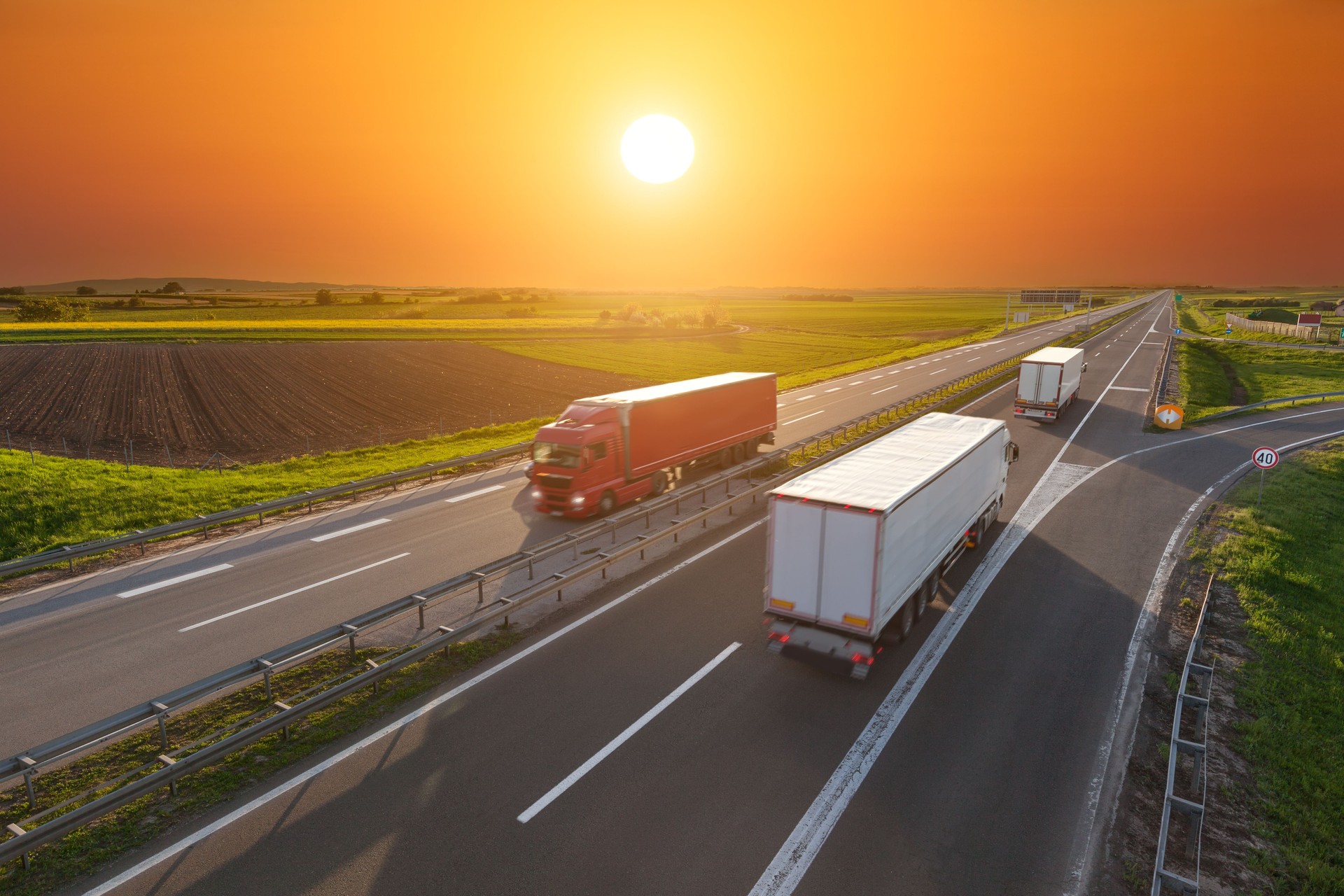 Speed delivery trucks on the empty highway at sunset